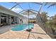 Screened pool with patio umbrella and tropical landscape and golf course views offer a serene outdoor living space at 265 White Marsh Ln, Rotonda West, FL 33947