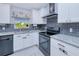 Bright kitchen features white cabinetry, stainless steel appliances and gray subway tile backsplash at 2685 Nanette Ln, North Port, FL 34286