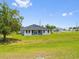 Beautifully landscaped backyard featuring lush green grass, young trees, and a view of the home's exterior at 27263 Deep Creek Blvd, Punta Gorda, FL 33983
