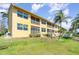 Exterior view of yellow building with multiple units, balconies, and well-maintained landscaping at 3228 Purple Martin Dr # 116, Punta Gorda, FL 33950