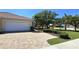 Charming single-story home showcasing a well-manicured lawn and a brick driveway leading to a two-car garage at 327 Monaco Dr # 12, Punta Gorda, FL 33950