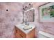 Charming powder room with palm wallpaper, updated lighting, and wood vanity at 4229 Cockrell St, Port Charlotte, FL 33948