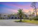 Charming multi-Gathering home featuring a garage, balcony, and lush green lawn with mature palm trees under a colorful sky at 4260 Placida Rd # 13B, Englewood, FL 34224