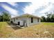 The back exterior view features a water heater, a well-kept lawn, and a clear sky at 5611 Ganyard Ave, North Port, FL 34291