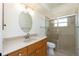 Bathroom showcasing a single sink vanity with a large mirror and tiled shower with glass doors at 5611 Ganyard Ave, North Port, FL 34291