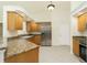 Well-lit kitchen featuring granite countertops, wood cabinetry, stainless steel refrigerator, and tile floors at 5611 Ganyard Ave, North Port, FL 34291