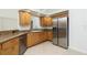 Kitchen showcasing stainless steel refrigerator, wood cabinets, granite counters, and tile flooring at 5611 Ganyard Ave, North Port, FL 34291