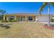 Charming yellow home with a manicured front lawn, palm tree, and white garage door at 6235 Bixel Ln, Englewood, FL 34224