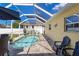 Screened-in pool area featuring blue tiled pool, brick pavers, and patio furniture at 6235 Bixel Ln, Englewood, FL 34224