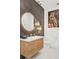 Stylish bathroom features a round illuminated mirror, wood vanity, and modern fixtures at 7200 Riverside Dr, Punta Gorda, FL 33982