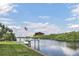 Scenic waterfront view with a private dock, boat lift, lush green lawn, and American flag waving in the breeze at 7200 Riverside Dr, Punta Gorda, FL 33982