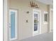 This exterior shows a shower, 2 white trimmed doors, art, and an exterior window on a tan concrete building at 7200 Riverside Dr, Punta Gorda, FL 33982