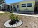 Yellow mobile home exterior with a small decorative garden at the front, complemented by lush landscaping at 805 S Green Cir, Venice, FL 34285