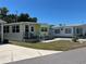 Exterior view of a charming yellow-colored mobile home with well-maintained landscaping and a driveway at 805 S Green Cir, Venice, FL 34285
