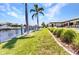 A waterfront backyard features lush green grass, swaying palm trees, and a serene view of the canal at 810 Napoli Ln, Punta Gorda, FL 33950