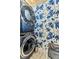 Modern laundry room with blue stackable washer and dryer and blue floral wallpaper at 810 Napoli Ln, Punta Gorda, FL 33950