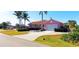 Property features a paved driveway, tropical palms, manicured landscaping, and an attached garage at 8233 Burwell Cir, Port Charlotte, FL 33981