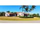 Inviting single-story home boasts a pristine lawn, tropical palm trees, and manicured shrubbery at 8233 Burwell Cir, Port Charlotte, FL 33981