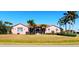 Charming single-story home with tile roof, beautiful lawn, and mature palm trees under a clear blue sky at 8233 Burwell Cir, Port Charlotte, FL 33981