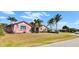 Charming pink single-story home with a well-manicured lawn and several mature palm trees at 8233 Burwell Cir, Port Charlotte, FL 33981