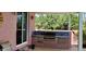 Covered outdoor kitchen featuring a brick counter with a built-in grill and tiled backsplash at 8233 Burwell Cir, Port Charlotte, FL 33981