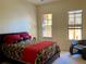 Comfortable bedroom featuring two windows, a chair and stylish red and black decor at 98 Vivante Blvd # 9834, Punta Gorda, FL 33950