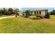 A lush green front lawn leads to this single-story home, showcasing tropical landscaping in the front yard at 11105 Pendleton Ave, Englewood, FL 34224