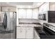Updated kitchen with stainless steel refrigerator, black appliances, granite countertops, and white cabinets at 11105 Pendleton Ave, Englewood, FL 34224