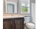 This bathroom showcases a vanity with dark wood cabinetry, a framed mirror, and a window at 11136 Grapefruit Ln, Punta Gorda, FL 33955