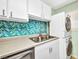 Close-up on a kitchen area showcasing stylish mosaic tile backsplash and a stackable washer and dryer at 150 Harborside Ave # 134, Punta Gorda, FL 33950