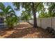 Spacious backyard featuring a screened pool, vinyl fence, mature trees, and a wood pile at 1773 Portage St, North Port, FL 34287