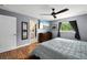 This bedroom features hardwood floors, a ceiling fan, a tv, and a doorway to an ensuite bathroom at 1773 Portage St, North Port, FL 34287