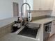 Close-up of stainless steel kitchen sink with modern faucet and soap dispensers on speckled countertop at 18135 Lake Worth Blvd, Port Charlotte, FL 33948