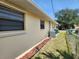 Side exterior showcasing maintained yard and plantings alongside a chain link fence at 21035 Exmore Ave, Port Charlotte, FL 33952