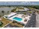 Aerial view of the community pool with lounge chairs, landscaping, and nearby buildings with ample parking at 25225 Rampart Blvd # 1801, Punta Gorda, FL 33983