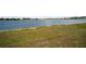 Scenic lake view with grassy shoreline and distant buildings under a partly cloudy sky at 26290 Rampart Blvd # D, Punta Gorda, FL 33983