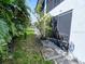 Exterior view of the back of the property showing tropical landscaping, a small patio, and screen door at 26485 Rampart Blvd # C1, Punta Gorda, FL 33983