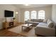 Bright living room featuring a comfortable gray sectional sofa, arched windows, and wood laminate flooring at 29211 Picador St, Punta Gorda, FL 33982