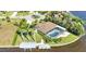Aerial view of a waterfront property featuring a screened pool, boat dock, and lush landscaping at 3016 Curry Ter, Port Charlotte, FL 33981