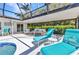Poolside seating area with turquoise lounge chairs and an outdoor sofa underneath a screened enclosure at 3016 Curry Ter, Port Charlotte, FL 33981