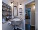 Bathroom with a unique corner sink, decorative mirror, and open shelving for linens and accessories at 3051 Chicory Ter, Punta Gorda, FL 33983