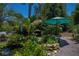 Lush landscaped yard with a rock-lined pond and small waterfall, highlighted by an umbrella and tropical plants at 3051 Chicory Ter, Punta Gorda, FL 33983