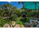 Serene backyard pond with a gentle waterfall, surrounded by lush tropical foliage and a relaxing seating area at 3051 Chicory Ter, Punta Gorda, FL 33983