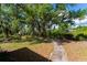 Expansive backyard featuring mature trees, lush landscaping, and a stone paver walkway at 3175 Lakatos St, North Port, FL 34286