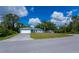 A blue home with a well-manicured lawn, attached garage, and mature trees in a residential neighborhood at 3175 Lakatos St, North Port, FL 34286