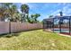 Screened-in pool in a lush, fenced backyard with mature palm trees offering privacy and shade on a sunny day at 428 Briarwood Rd, Venice, FL 34293