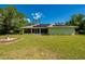 Expansive backyard featuring green lawn, mature trees, and solar panels on the roof at 4461 La France Ave, North Port, FL 34286