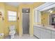 Bright yellow bathroom featuring a toilet, walk-in shower and vanity at 4461 La France Ave, North Port, FL 34286
