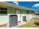 Side of the home showing the green exterior, AC unit, garbage can, and back door at 4461 La France Ave, North Port, FL 34286