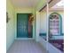 Inviting front porch with tiled floor, teal door and decorative hanging plants at 4461 La France Ave, North Port, FL 34286
